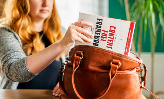Woman placing a book into a brown leather handbag