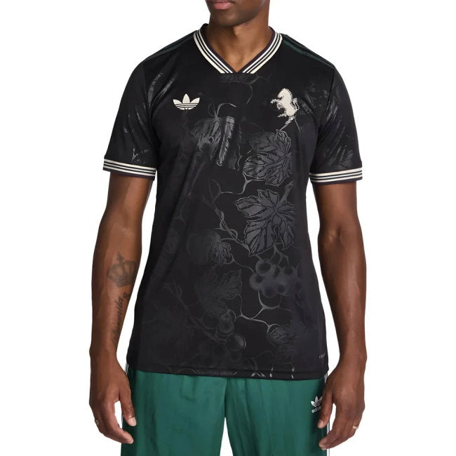 A man wearing a black short-sleeve V-neck t-shirt with a subtle floral vine pattern, featuring white striped trim on the collar and cuffs, and a white trefoil logo on the chest.