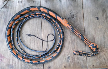 Black and orange braided whip on a wooden surface